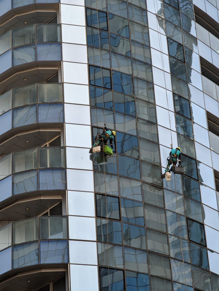 about-04 Professional window cleaners working on a skyscraper in Abu Dhabi, showcasing urban architecture.